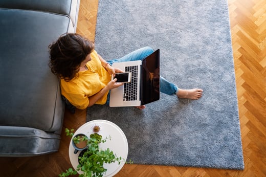 A woman relaxing at home with her phone and laptop